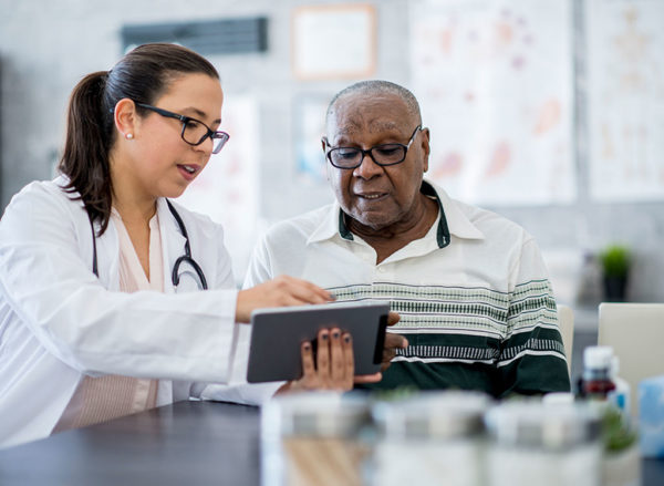 medical professional looking over information on a tablet with a client